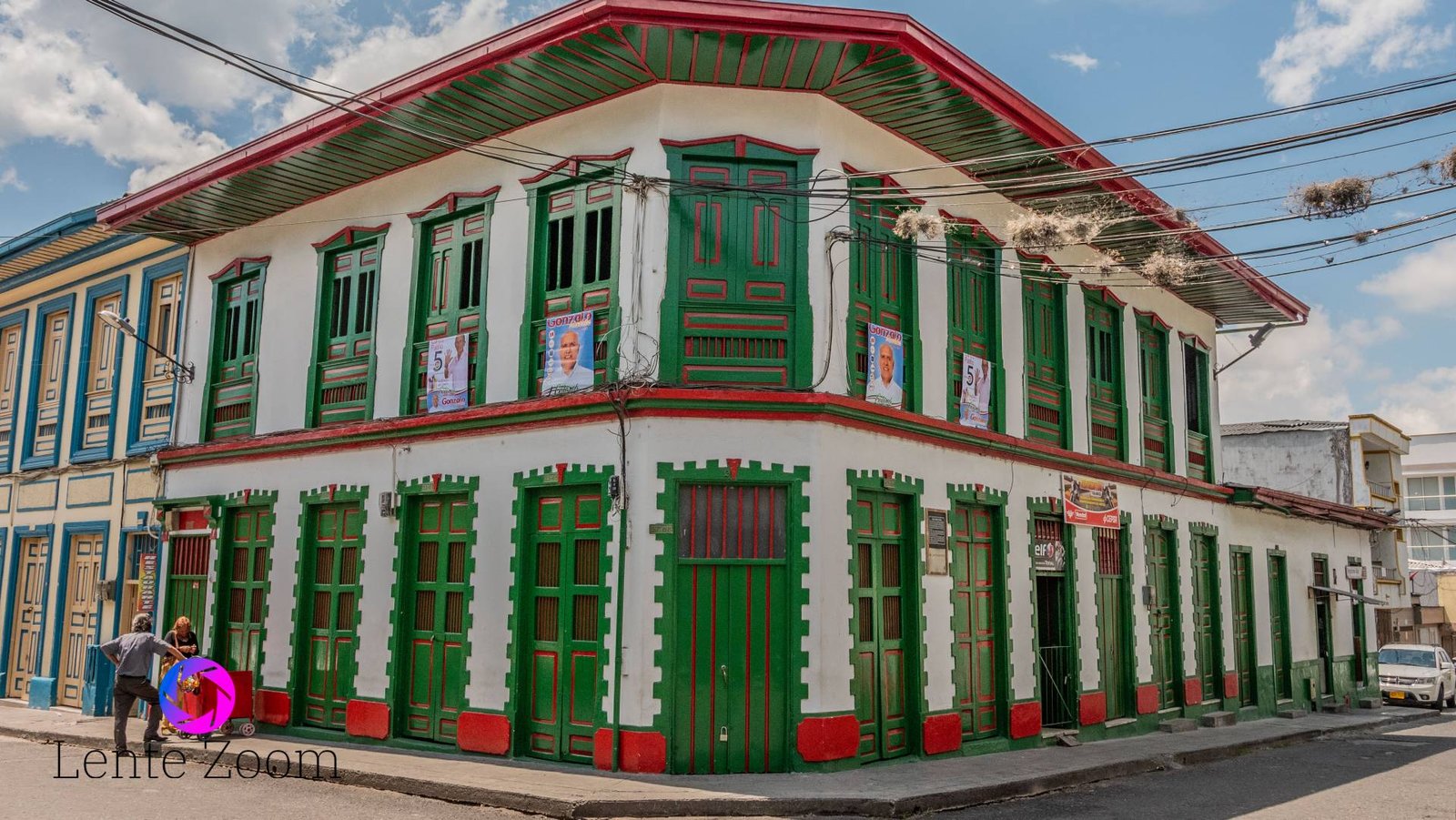Una casa esquinera muy grande de color blanco con verde y rojo
